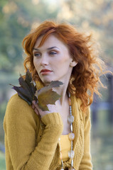 close up of red-haired woman with some leaves near face