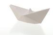 Paper boat on reflecting white background