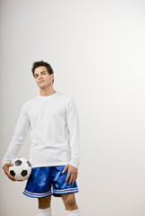 Serious soccer player in uniform holding soccer ball