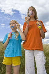 Wall Mural - Children blowing bubbles on summer meadow