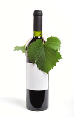 Wall Mural - Close up of a bottle of red wine with a grapes leaf