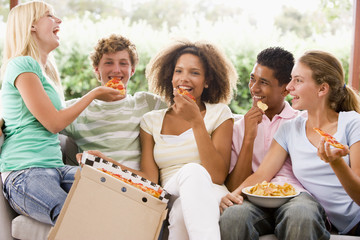 Group Of Teenagers Sitting On A Couch Eating Pizza