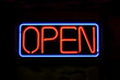 A neon OPEN sign glowing red in the window of a restaurant.