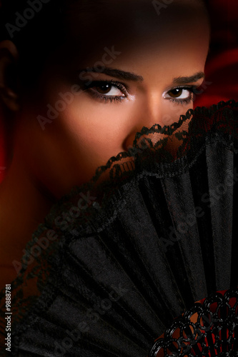Fototapeta do kuchni woman covering her face with a lacy fan, showing only the eyes