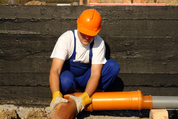 Poster - Plumber assembling pvc sewage pipes in house foundation