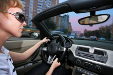 Young Woman Driving Convertible Car In City. Wide Angle View.