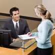 Receptionist greeting woman at front desk