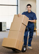 © AVAVA - Delivery man pushing stack of cardboard boxes on dolly