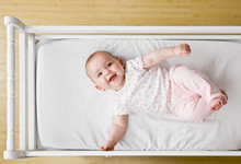 Happy, Playful Baby Laying In Crib