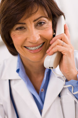 Wall Mural - Senior female doctor calling on phone, smiling.