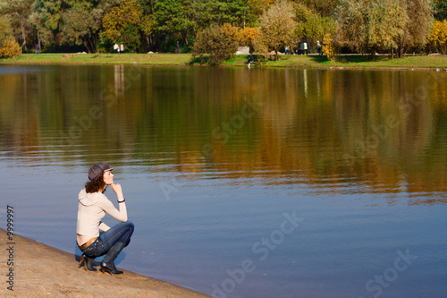 Photographie Young pretty woman sitting on the border of a river