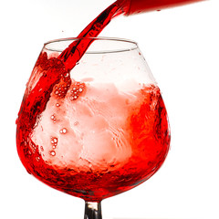 Red wine pouring into glass studio isolated on white background