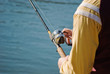 © Brent - Person holding a fishing rod and reel near a lake