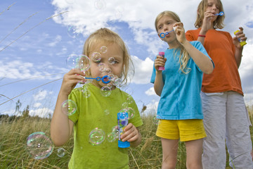 Wall Mural - Children blowing bubbles on summer meadow