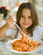 young girl eating spaghetti in restaurent