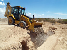A Construction Back Hoe Filling In A Trench.