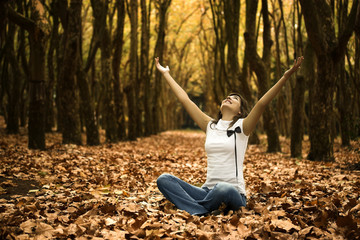 Wall Mural - Happy woman seated on the ground with arms open