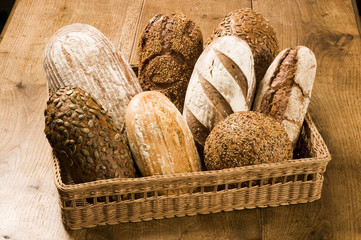 Canvas Print - Basketful of different types of bread on a wooden table