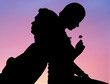 © pressmaster - Silhouette of romantic couple sitting back to back