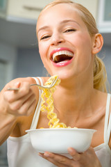 Wall Mural - Young happy woman with plate of spaghetti at kitchen