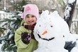Happy little girl hugging her snowman