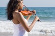 © michaeljung - young indian woman play violin on beach