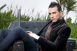 © Tandem - beautiful man with laptop sitting in an armchair in the forest