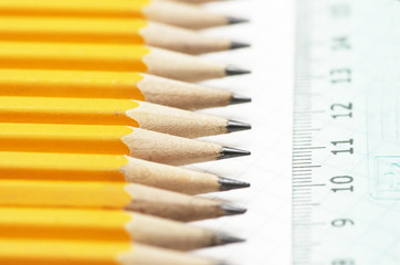 set of well sharpened pencils near ruler