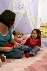mother removing her daughter's sock while sitting on the bed