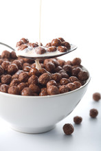 milk pouring into bowl with chocolate balls isolated