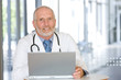 © carlosseller - Portrait of a  senior caring doctor working on laptop