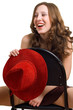 Laughing girl with a red hat sits astride on a chair