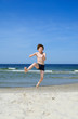 © Jacek Chabraszewski - Boy jumping on beach against blue sky
