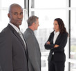 © WavebreakMediaMicro - Serious business leader looking at camera in front of team