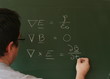 Teacher writing Maxwell's equations on chalkboard