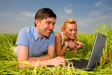 Wall Mural - Casual happy couple on a laptop computer outdoors