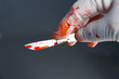 Gloved hand holding scalpel with blood
