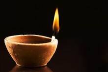 Single Burning Flame In An Earthen Lamp On A Black Background