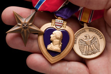 Man Holding Purple Heart, Bronze And National Defense War Medals