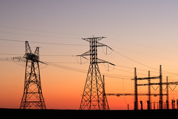  Silhouetted power pylons against a red sky at sunset