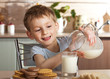 Leinwanddruck Bild - Healthy child pours milk from jug