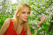 © Sergios - Young woman in red dress enjoying smell of blooming tree