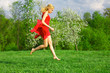 © Sergios - Young beautiful woman in a red dress jumping on lawn