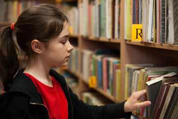 Wall Mural - Young girl in library looking for books