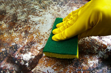Gloved Hand Scrubbing A Dirty Metal Surface