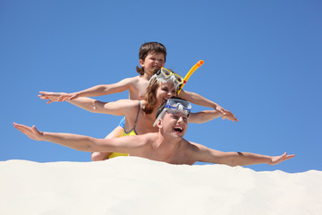 family with son lying on sand with hands up