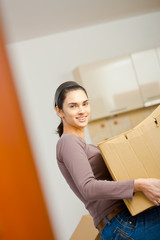 Canvas Print - Young woman lifting cardboard box