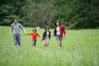 © auremar - Couple avec enfants courant dans l'herbe à la campagne