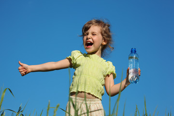 screaming girl in grass with plastic bottle with water