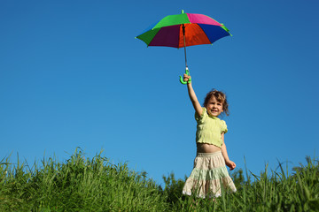 Wall Mural - girl with multicoloured umbrella in lifted hand in grass